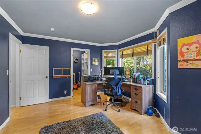 An additional angle of the spacious secondary bedroom reveals crown molding and bright floors. The bayed window layout enhances natural light and architectural character.