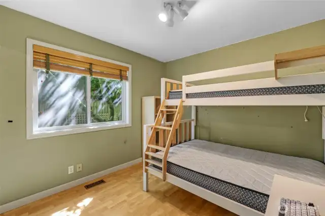 The third bedroom overlooks the private backyard and provides a cozy setting for restful sleep or imaginative play. Its warm-toned flooring and ample window make it feel fresh and open.