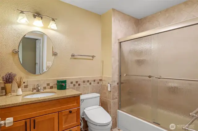 The full hall bath was thoughtfully updated and features classic tilework, a granite-topped vanity, and a full tub with shower. A perfect blend of function and warmth for household use or guests.