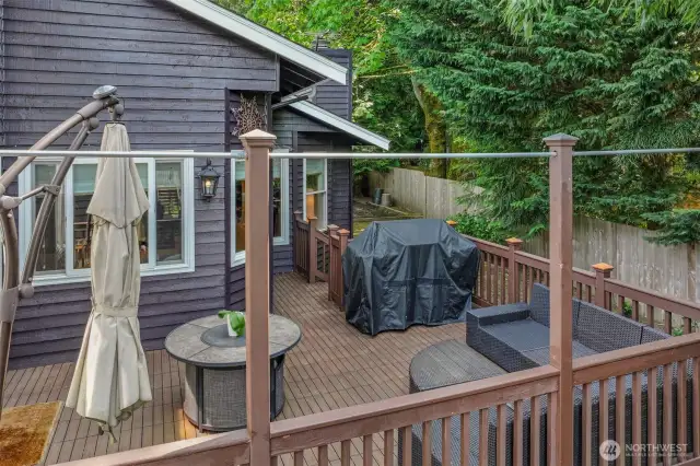 This angle captures the layout of the deck and its direct access to the yard. Surrounded by evergreens, this area offers a tranquil escape ideal for grilling, lounging, or dining al fresco.