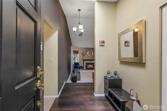 Step inside to a spacious foyer with vaulted ceilings and a stylish chandelier overhead. Rich hardwood flooring and an open sightline to the living area create an inviting first impression as you enter the home.