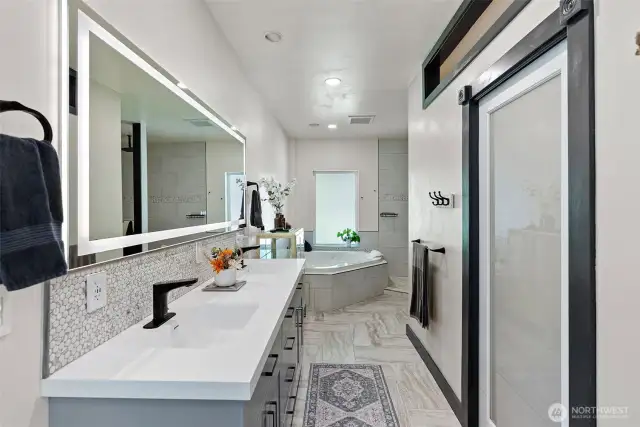 Remodeled bathroom comes with a double vanity, jetted tub, and a tiled walk-in shower.