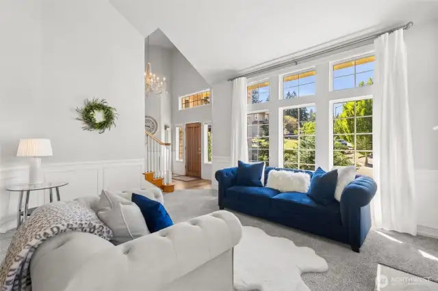 Grand Entry & Sunlit Living Room - welcome guests with this grand entryway showcasing a warm wood staircase and stunning floor-to-ceiling windows. The spacious living area offers abundant natural light and serene views of the manicured front yard.