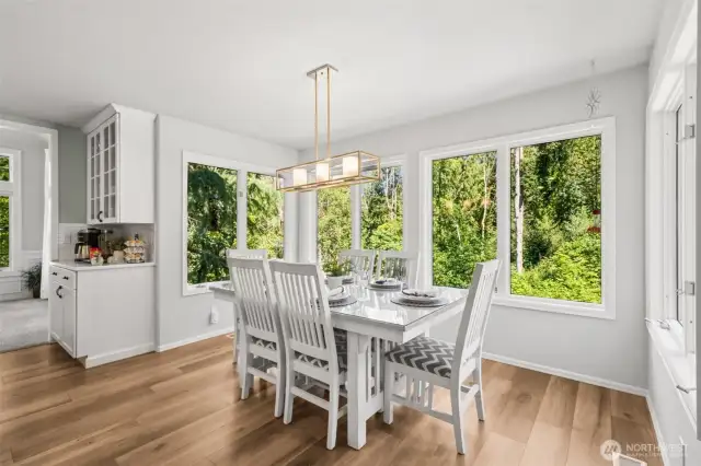 Scenic Breakfast Nook with Tree-Lined Views  Start your mornings in this charming breakfast nook framed by panoramic windows showcasing serene greenbelt views. Features include a stylish modern light fixture, built-in coffee station, and ample space for casual dining.