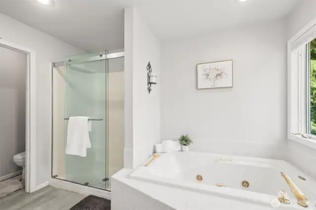 Spa-Inspired Ensuite with walk-in closet and a Jetted Tub. Unwind in your private ensuite complete with a large jetted soaking tub, glass-enclosed shower, and serene backyard views. A soothing, spa-like experience right at home.