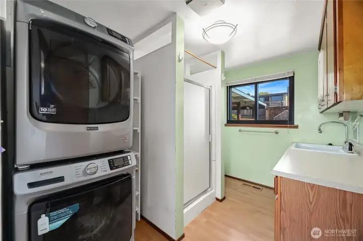 UTILITY / MUD ROOM / PANTRY with 3/4 BATH  Maytag stacking washer and dryer  Shower / toilet / canned goods built in storage rack  Utility sink with counter and storage cabinet  Window to rear with views of yard