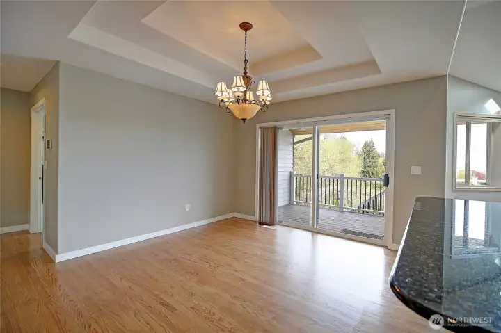 Bright dining space with elegant tray ceiling and outdoor access.