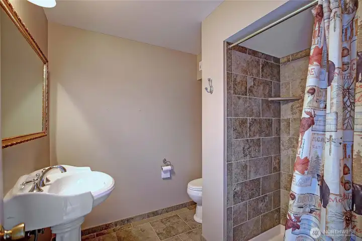 Lower-level bathroom with walk-in shower and tile finishes.