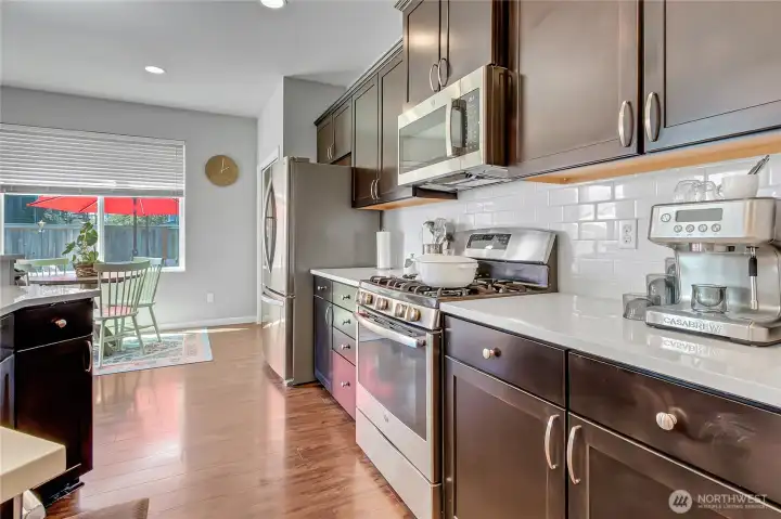 Quartz counters and tile backsplashes are a beautiful contrast to your cabinets!  Just past the stainless refrigerator is your pantry.