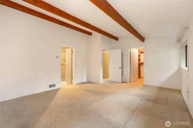 Another view of the primary bedroom. The door on the left leads to the en suite bathroom, the middle door out to the hallway and the one on the right is the walk-in closet.