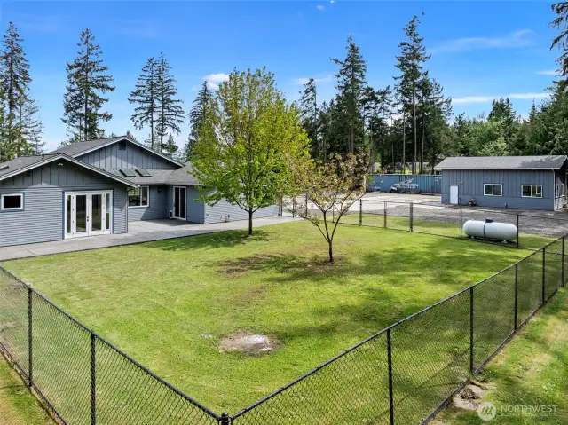 Here you can see the fenced yard, back patio. French doors to Primary suite, other door to access mudroom and bathroom. 2 OWNED propane tanks on property.