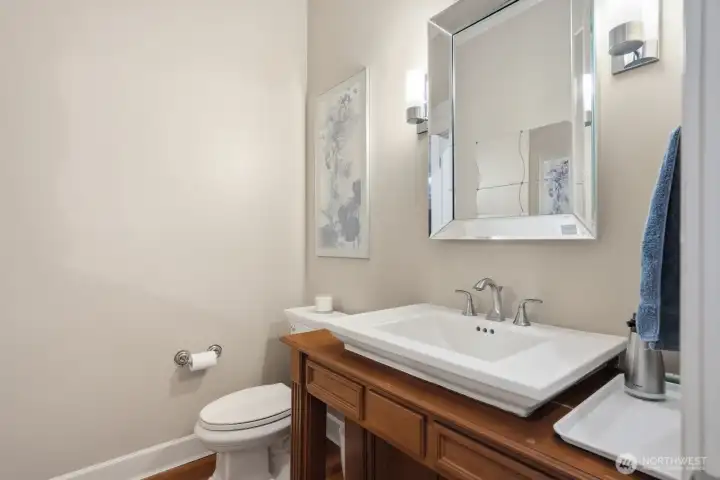 The powder bath off the foyer hallway with furniture style vanity and sconce lighting.
