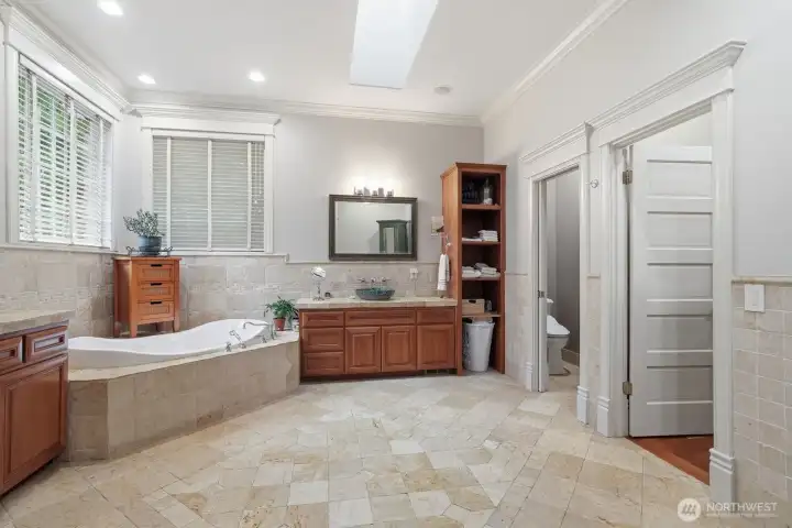 The ensuite bathroom features beveled travertine floors, travertine wainscoting around the soaking tub.