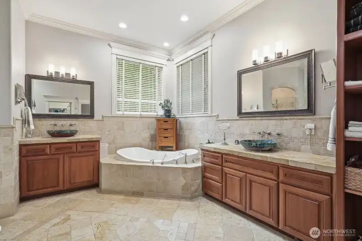 Separate cherry vanities and a walk-in stone shower.