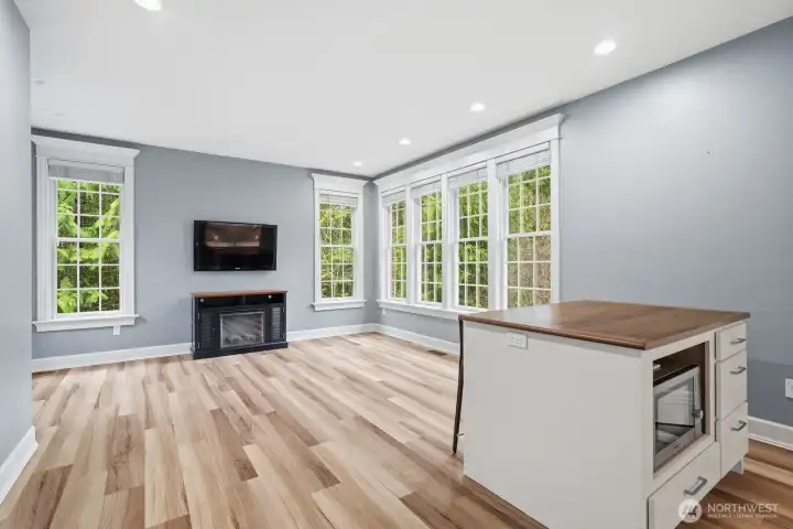 The bonus room features engineered hardwood floors, an island with seating and microwave.