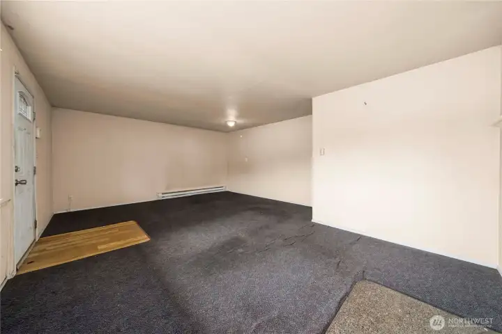 Living room and front entry as seen from the fireplace corner. On the left is the front entry and on the right is the hall and kitchen