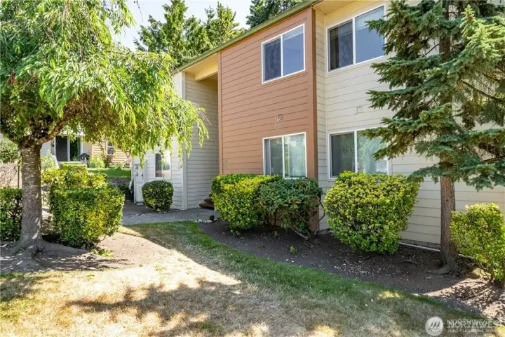 Exterior view of Valley High Condominiums in Kent, Washington, featuring mature trees, landscaped grounds, and a peaceful residential setting on East Hill.
