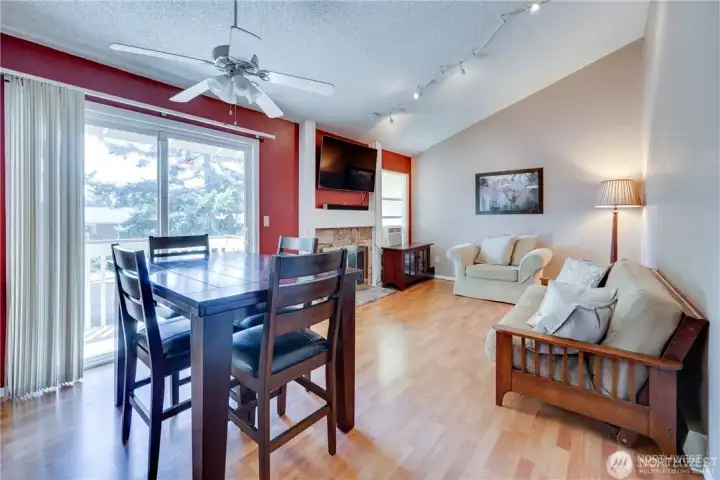 Open-concept living and dining room with vaulted ceilings, wood-burning fireplace, laminate flooring, and private deck access in a move-in ready condo on Kent's East Hill.
