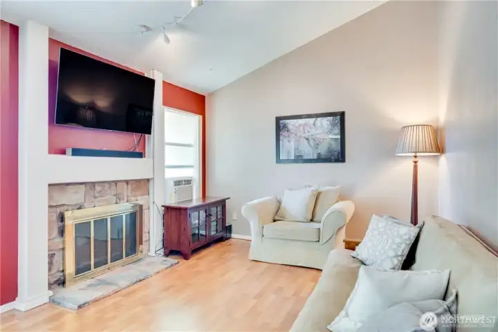 Living room with wood-burning fireplace, stone surround, laminate flooring, and open-concept layout in a move-in ready condo on Kent's East Hill.