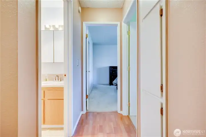 Interior hallway leading to bedrooms and bathrooms with neutral finishes and functional layout in a move-in ready 2-bedroom condo.