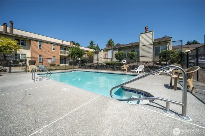 Community swimming pool with lounge area and surrounding condominium buildings, offering residents convenient recreational amenities and outdoor enjoyment.