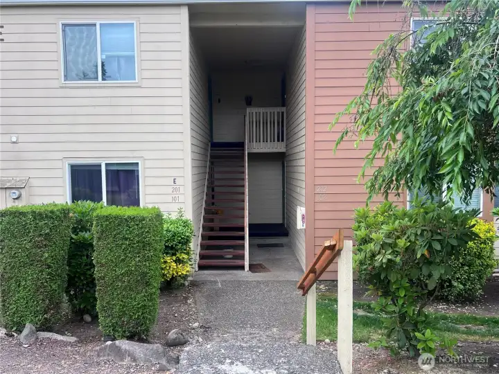 Front entrance of condominium residence with covered entry, landscaped walkway, and attractive exterior in a well-maintained community.