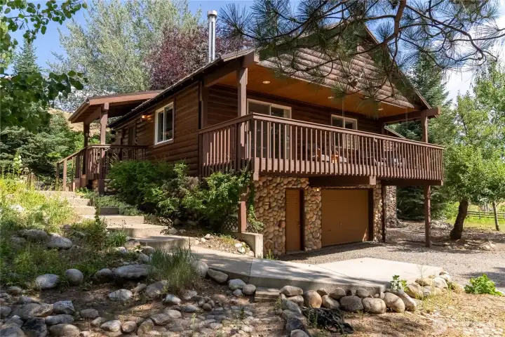 Attractive log-sided home with stone accents, mature trees, and inviting outdoor living spaces. Attractive log-sided home with stone accents, mature trees, and inviting outdoor living spaces.