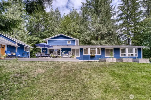 The backyard is private, facing the woods and creek. The guest cottage is to the left of the main house.