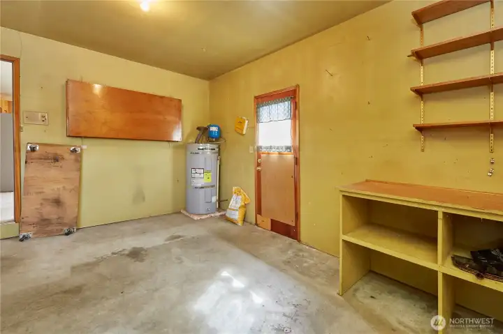 Another View of Garage With Newer Water Heater; Door to Backyard and Wall Storage Unit