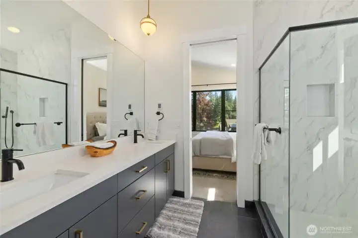 Spa-inspired primary bath with a dual sink vanity and a large glass enclosed shower. Spa-inspired primary bath with a dual sink vanity and a large glass enclosed shower.