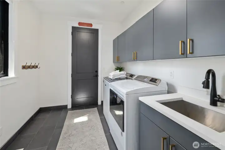Main level laundry room with built-in cabinetry and convenient sink. Main level laundry room with built-in cabinetry and convenient sink.