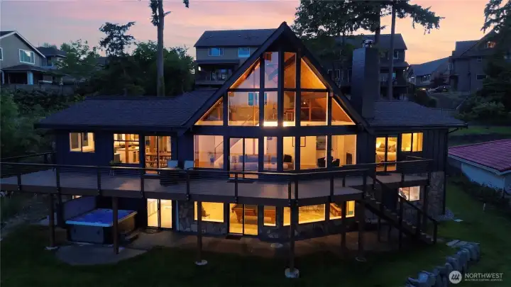 When the lights come on at night, this home is pure magic. The glowing A-frame, multi-level deck, and hot tub tucked below tell the whole story of waterfront living done right.