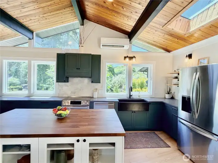 The updated main floor kitchen is a showstopper in every direction. Vaulted A-frame ceilings with wood planking, skylights, dark cabinetry, a farmhouse sink, stone backsplash, butcher block island, and stainless steel appliances make this the kitchen you have always wanted. All appliances stay.