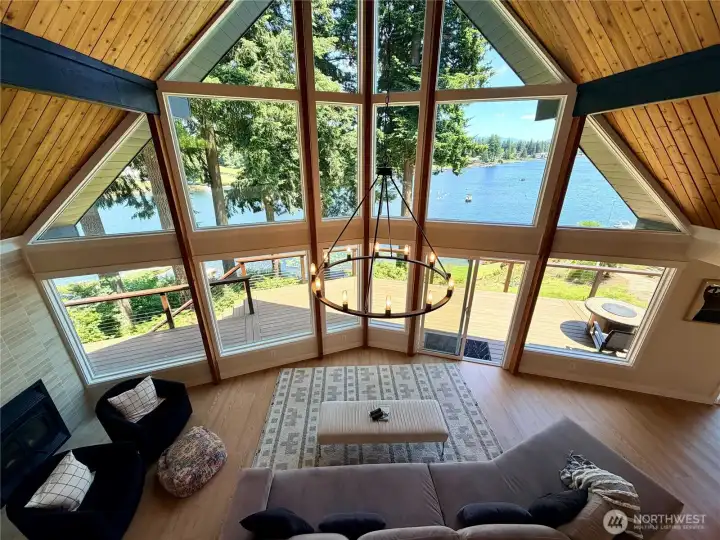From the loft, the full drama of this home reveals itself. The soaring A-frame window wall frames Lake Meridian from above, with the great room below and the composite deck and flat lakeside yard visible beyond. There is simply nothing else like this on the water.