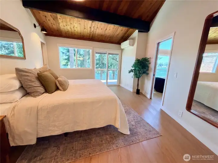 The primary suite on the main-level features a wood plank ceiling, mini split for year-round comfort, and a slider that opens directly onto the expansive composite deck with lake views. Wake up to the water every single morning.