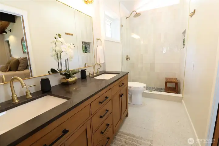 The spa-like primary ensuite is completely updated with a double vanity, warm wood cabinetry, dark stone countertops, brushed gold hardware, heated floors, and a stunning walk-in tile shower. Every detail was chosen with care, and it shows.