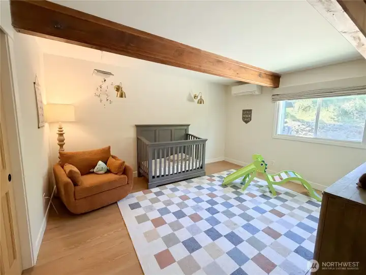 Soaring wood beams and brand new floors make every room in this home feel special, even this cozy main-level bedroom currently used as a nursery. Your vision, your space.