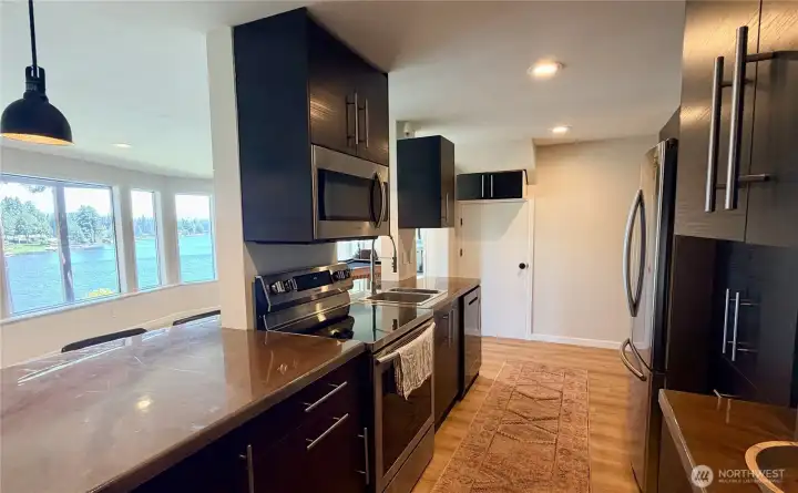 The daylight basement full kitchen features dark cabinetry, updated stainless steel appliances, and a large window looking directly out to the lake. Everything you need for multigenerational living or income-producing rentals, all with a view.
