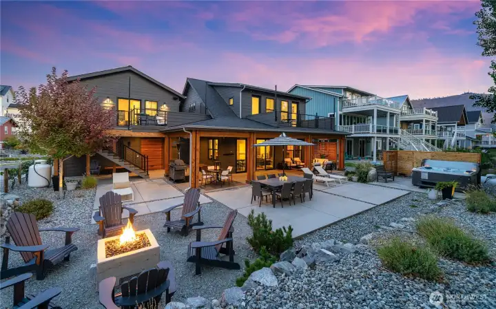 View of home and outdoor living area with lounge, dining and BBQ area and private hot tub and fire pit.