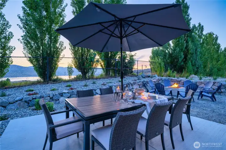 View of outdoor living area with dining table and spacious lake view patio with private hot tub, lounge area, built-in radiant patio heaters and fire pit and seating area.