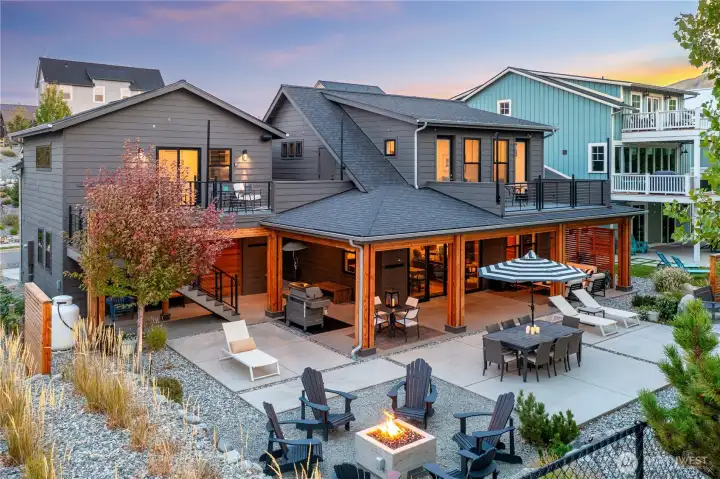 Exterior view of home and oversized west-facing lake view outdoor living area with outdoor dining, BBQ and lounge areas, built-in radiant patio heaters, cedar detailing, private hot tub and fire pit seating area.