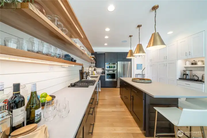 Kitchen with quartz countertops, high-end appliances, open shelving and a sit up island.