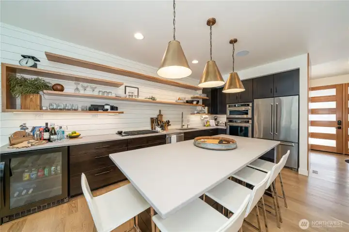 Kitchen with quartz countertops, high-end appliances, open shelving and a sit up island.