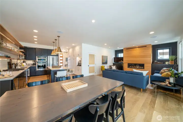 Main level kitchen with dining table with built in bench seating and living room with fireplace and glass doors leading to the outdoor living area.