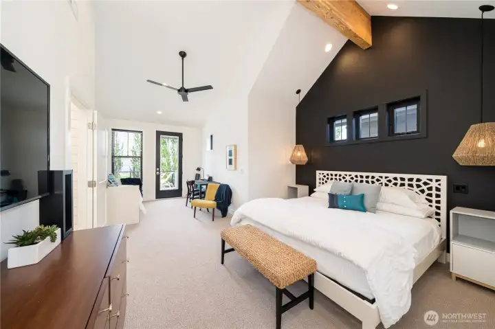 Upper level King ensuite bedroom 1 with vaulted ceilings, sitting area with bonus twin daybed and trundle for two additional guests, a work station,  and glass doors leading to the outdoor lake view deck.