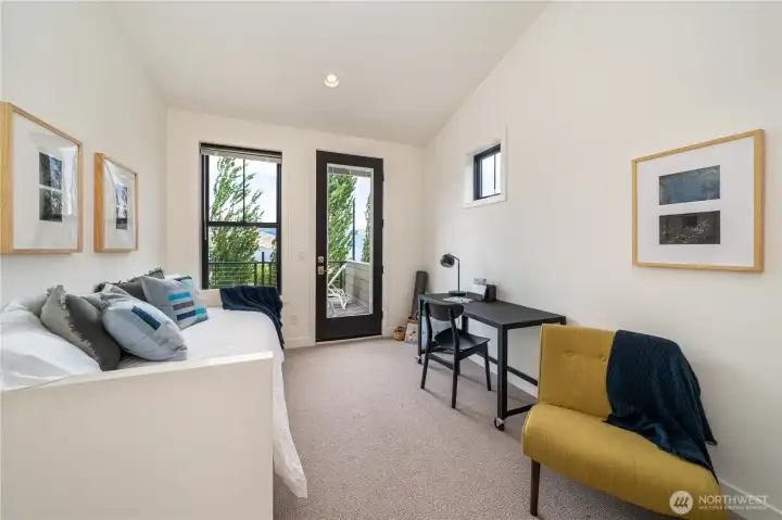 View of upper level King ensuite bedroom 1 with sitting area with bonus twin daybed and work area and French doors leading to the lake view deck.