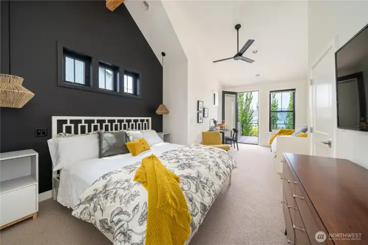 Upper level King ensuite bedroom 2 with vaulted ceilings, sitting area with bonus twin daybed and trundle for two additional guests, a work station, and glass doors leading to the outdoor lake view deck.
