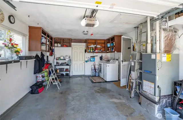 Utility Room: Located in the garage. The door to the right leads into the home; the rear door opens to a beautifully maintained backyard. Extra built-in storage cabinets provide added functionality.