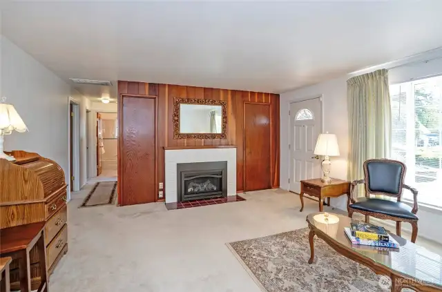 Rich wood trim frames the gas fireplace, enhancing the ambiance of this serene and welcoming living room.