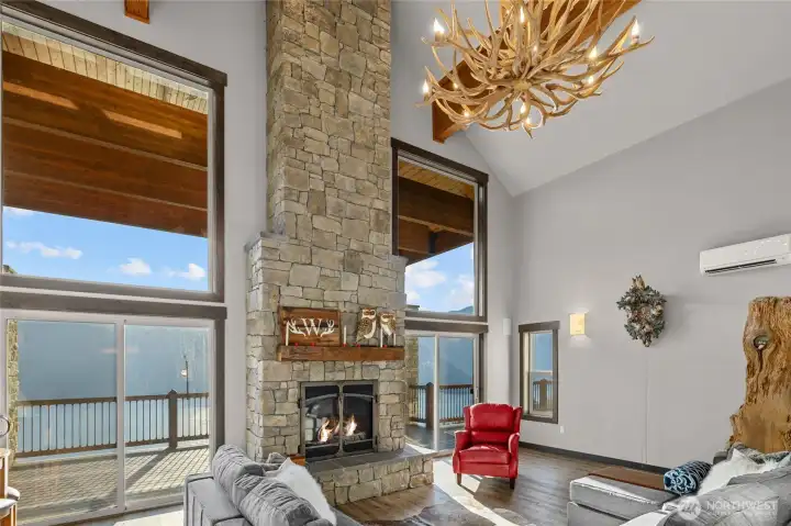 View of the living room fireplace, antler chandelier, and floor to ceiling windows to enjoy a view like no other.